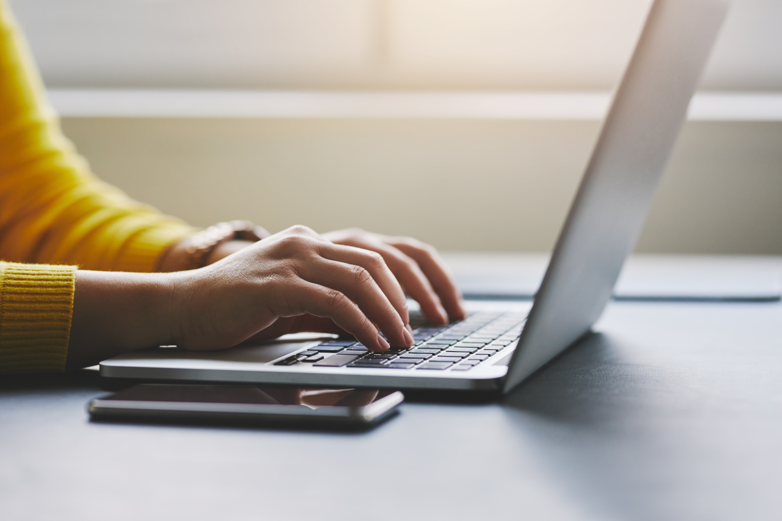 Person at desk with laptop and mobile device creating forms on the NestForms offline survey app platform