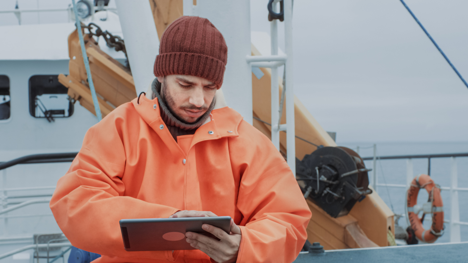 A person involved in the fisheries industry onboard a trawler with smart device using the NestForms offline survey app